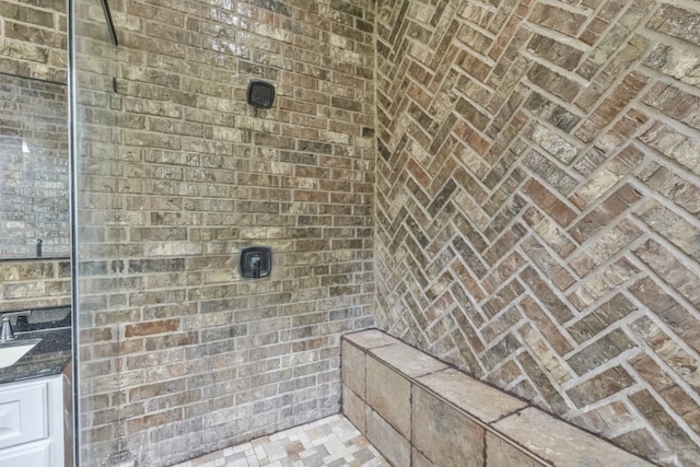 bathroom with walk in shower, vanity, and brick ceiling