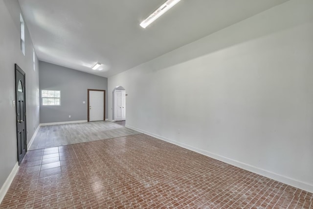 spare room with tile floors and vaulted ceiling