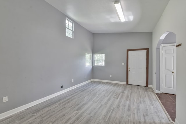 spare room featuring light hardwood / wood-style floors and a high ceiling