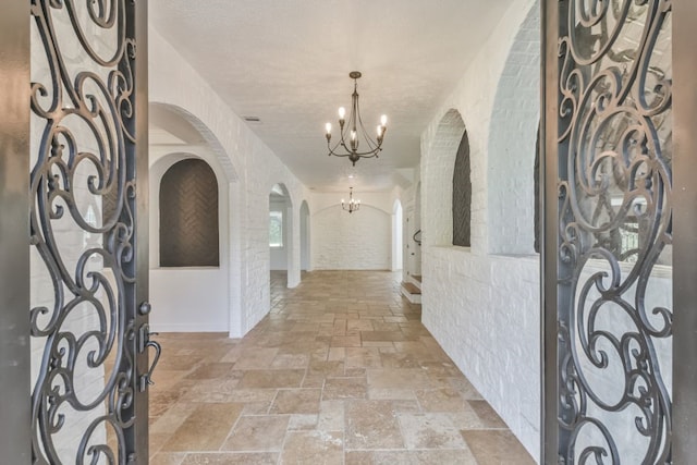 tiled foyer entrance featuring a notable chandelier and a textured ceiling