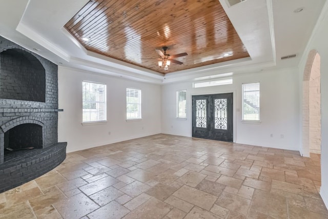 unfurnished living room with a brick fireplace, light tile floors, a raised ceiling, and wood ceiling