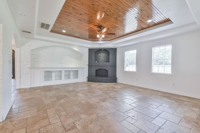 unfurnished living room with wooden ceiling, a brick fireplace, ceiling fan, and a raised ceiling