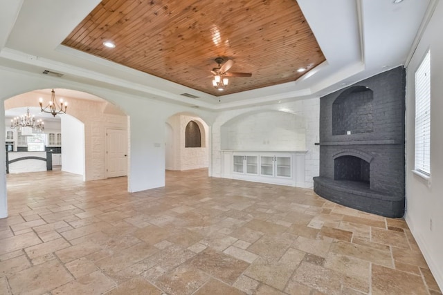 unfurnished living room with a tray ceiling, a brick fireplace, wooden ceiling, and ceiling fan with notable chandelier