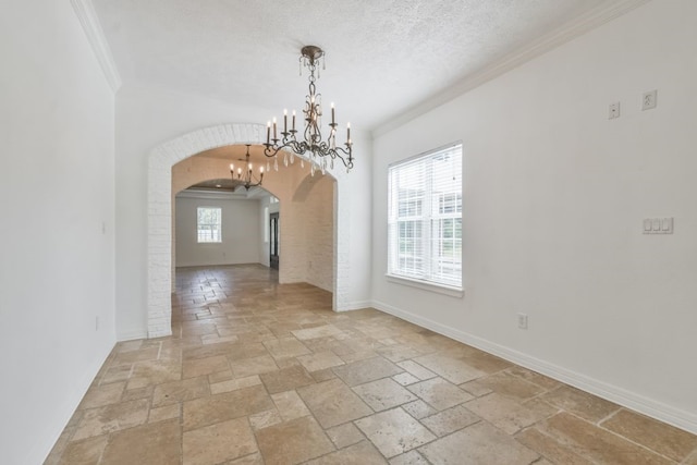 tiled spare room with a chandelier, a textured ceiling, and ornamental molding