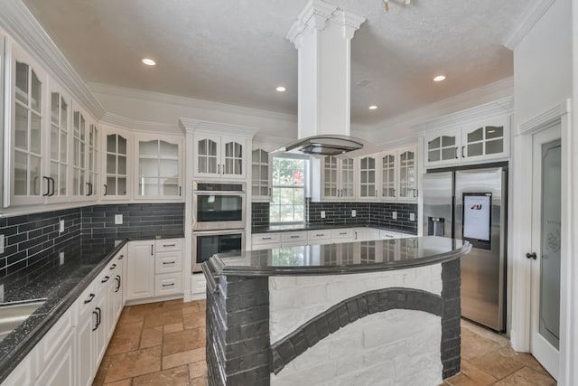 kitchen with stainless steel appliances, island exhaust hood, backsplash, white cabinetry, and dark stone countertops