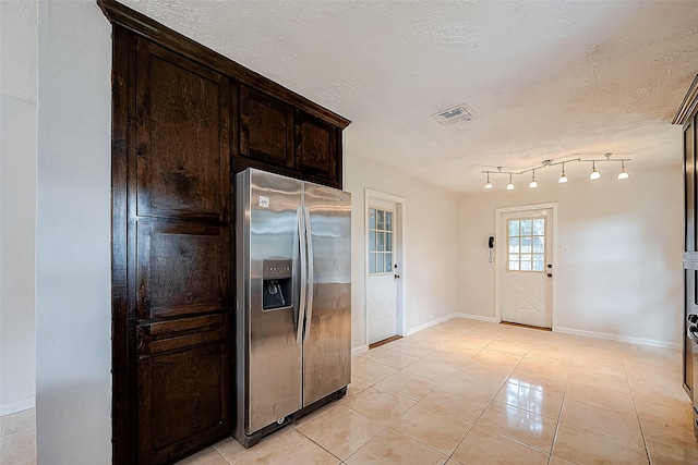 kitchen with a textured ceiling, dark brown cabinets, light tile patterned floors, and stainless steel refrigerator with ice dispenser