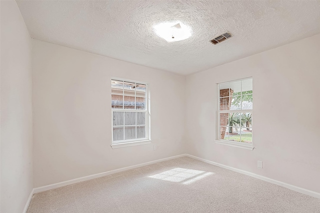 carpeted empty room featuring a textured ceiling