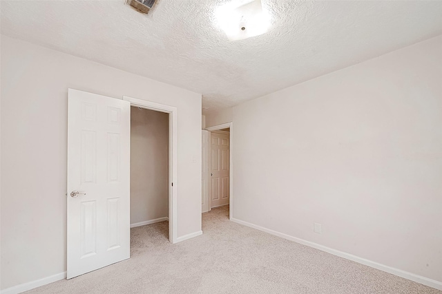 unfurnished bedroom with a closet, light colored carpet, and a textured ceiling