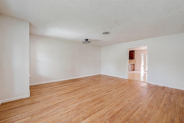 spare room featuring light hardwood / wood-style flooring and a textured ceiling