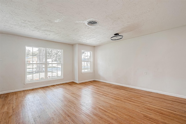 unfurnished room featuring a textured ceiling, light hardwood / wood-style flooring, and plenty of natural light