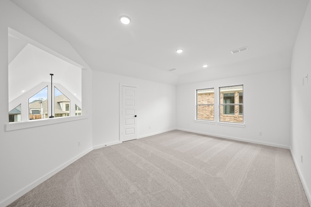 carpeted empty room featuring vaulted ceiling