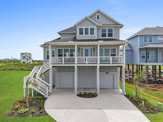 coastal inspired home with covered porch, a front yard, and a garage