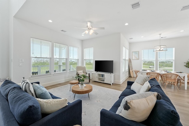 living room featuring ceiling fan with notable chandelier, light hardwood / wood-style flooring, and a healthy amount of sunlight