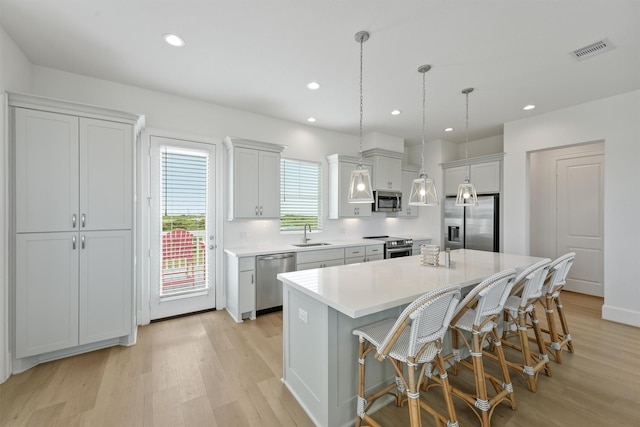 kitchen featuring pendant lighting, sink, a kitchen island, a kitchen bar, and stainless steel appliances