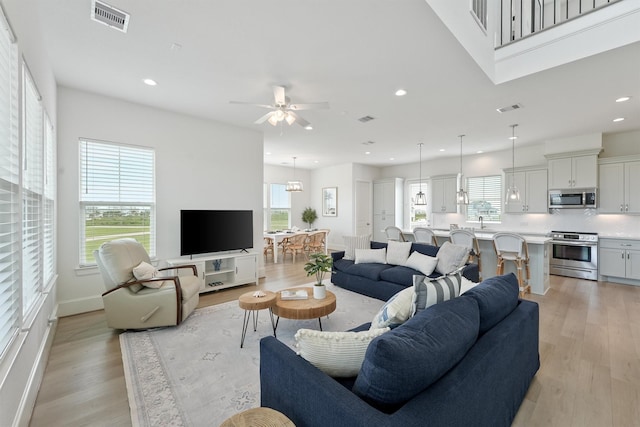 living room with light hardwood / wood-style flooring, ceiling fan, and sink