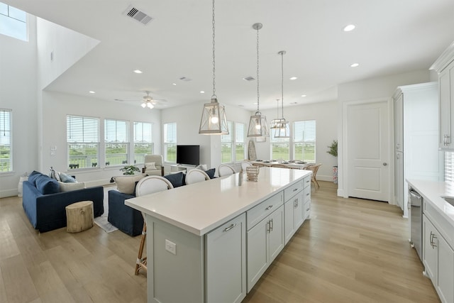 kitchen featuring a breakfast bar, a center island, white cabinets, hanging light fixtures, and ceiling fan