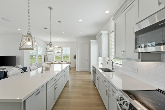 kitchen with appliances with stainless steel finishes, tasteful backsplash, sink, a kitchen island, and hanging light fixtures