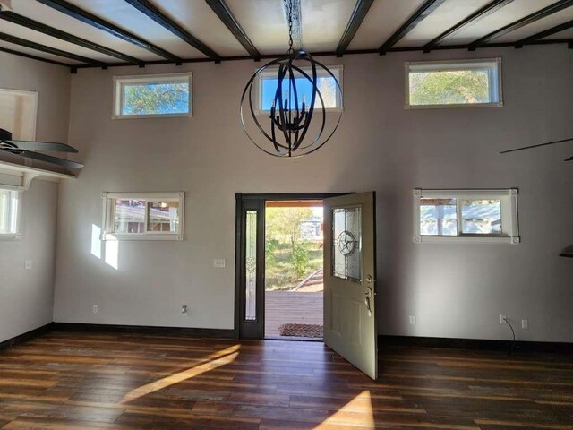 foyer with beamed ceiling, a towering ceiling, dark hardwood / wood-style flooring, and a chandelier