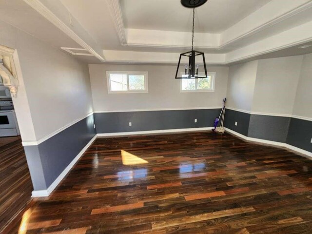 unfurnished dining area with plenty of natural light, a chandelier, dark hardwood / wood-style flooring, and a tray ceiling