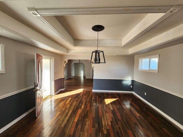 unfurnished dining area featuring a raised ceiling and dark hardwood / wood-style floors