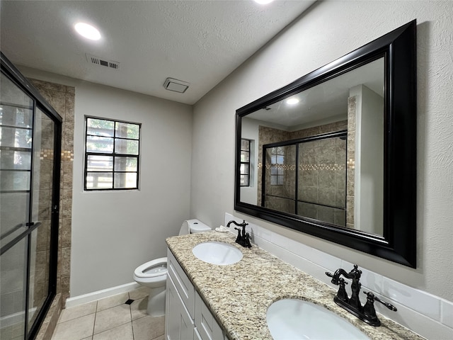 bathroom featuring double vanity, tile flooring, a textured ceiling, a shower with shower door, and toilet