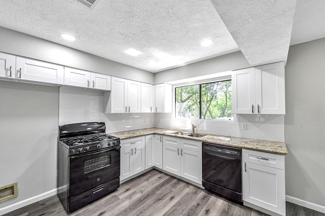 kitchen featuring black appliances, white cabinets, and light hardwood / wood-style floors