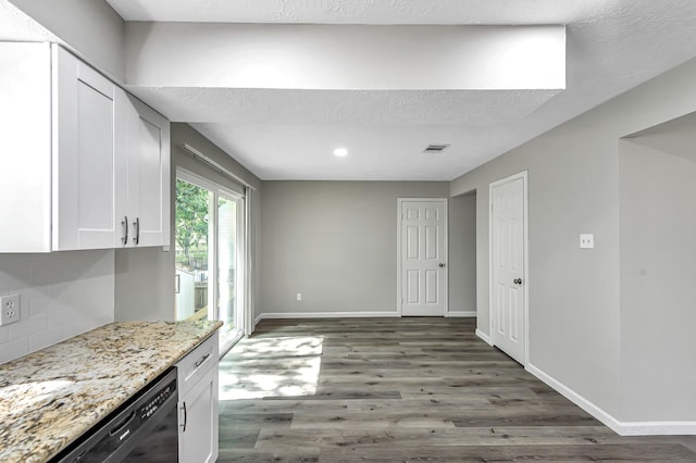 kitchen with backsplash, black dishwasher, hardwood / wood-style floors, white cabinetry, and light stone countertops