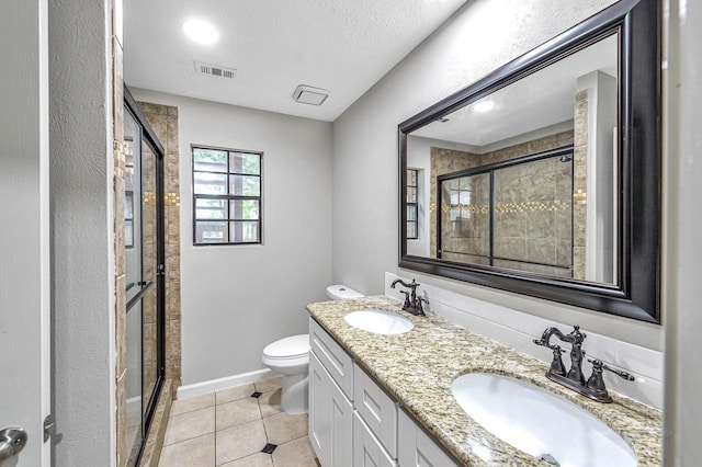 bathroom with oversized vanity, toilet, tile flooring, double sink, and a textured ceiling