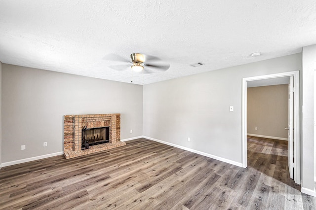 unfurnished living room featuring a textured ceiling, a brick fireplace, ceiling fan, and hardwood / wood-style floors