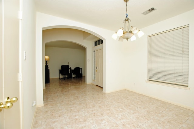 empty room featuring light tile patterned flooring and a chandelier