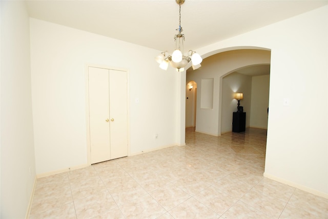 tiled empty room featuring a notable chandelier