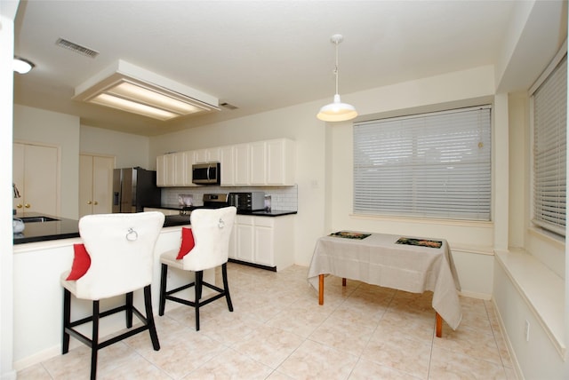 kitchen with decorative backsplash, a kitchen bar, stainless steel appliances, sink, and pendant lighting