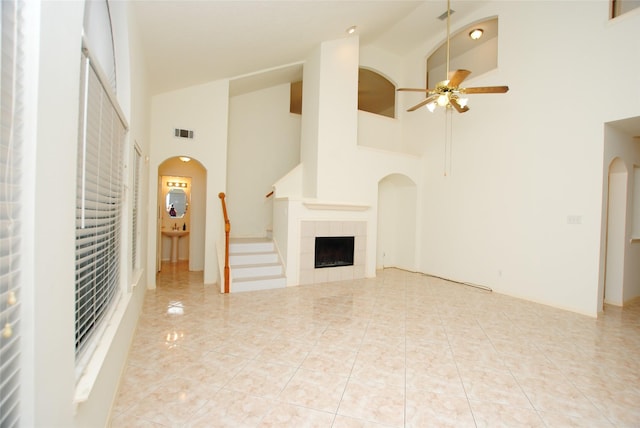 unfurnished living room featuring a tile fireplace, light tile patterned floors, high vaulted ceiling, and ceiling fan