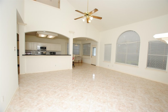 unfurnished living room with light tile patterned floors, high vaulted ceiling, and ceiling fan