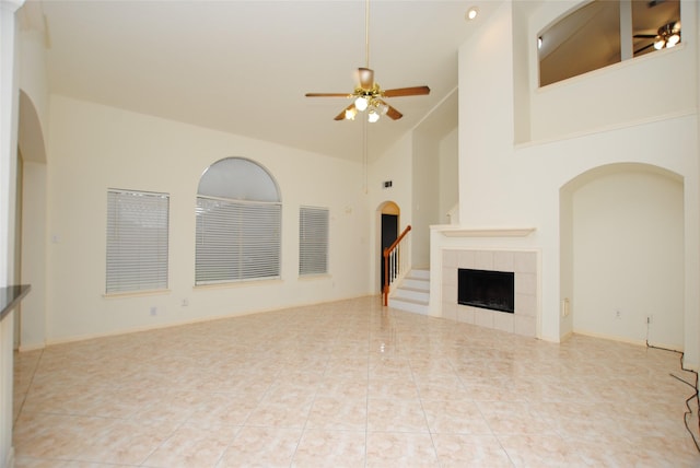 unfurnished living room featuring a fireplace, light tile patterned floors, high vaulted ceiling, and ceiling fan