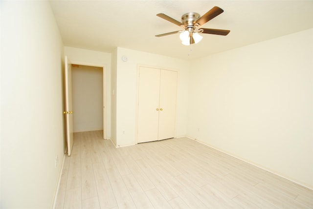 unfurnished bedroom with ceiling fan, light wood-type flooring, and a closet