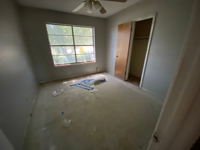 unfurnished bedroom with ceiling fan and a closet