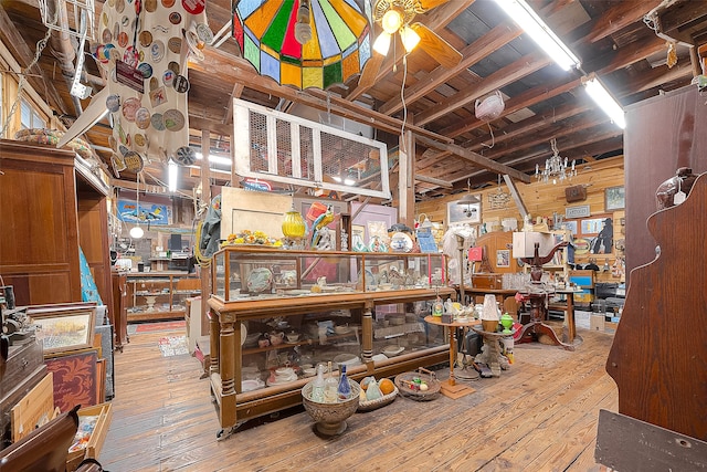 misc room featuring ceiling fan, wooden walls, and light hardwood / wood-style floors