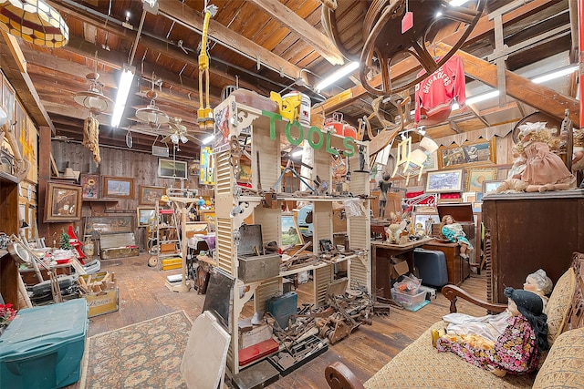 misc room featuring wooden walls, wood ceiling, wood-type flooring, a workshop area, and beam ceiling