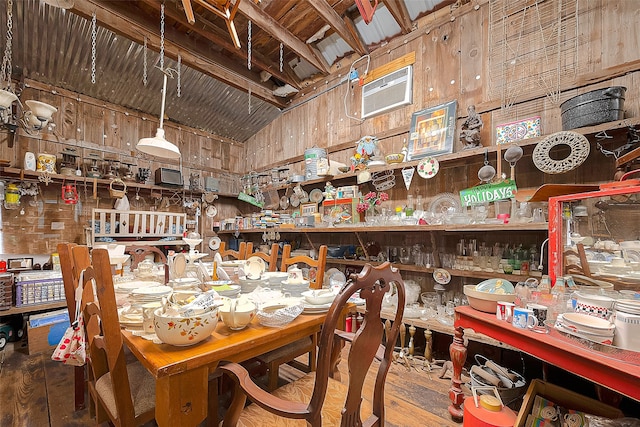 dining room with wood walls, beamed ceiling, wood-type flooring, an AC wall unit, and high vaulted ceiling