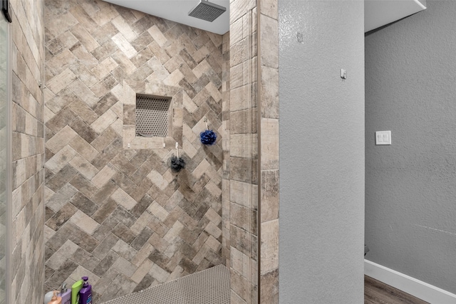 interior details featuring a tile shower and wood-type flooring