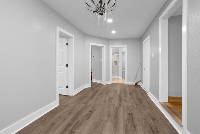 hallway with hardwood / wood-style flooring and a chandelier