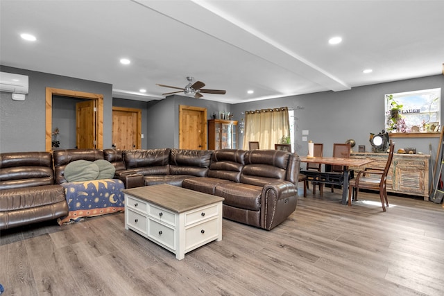 living room featuring light hardwood / wood-style floors, a wall mounted air conditioner, and ceiling fan