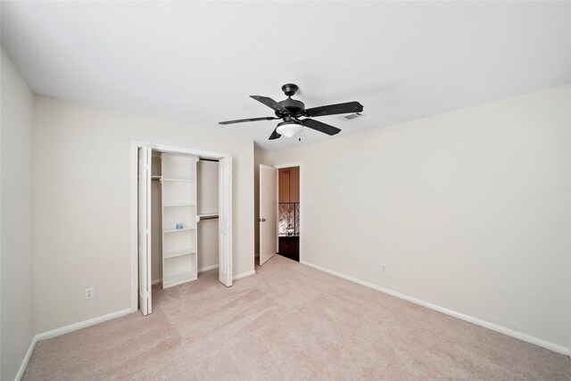 unfurnished bedroom with a closet, ceiling fan, light colored carpet, baseboards, and visible vents