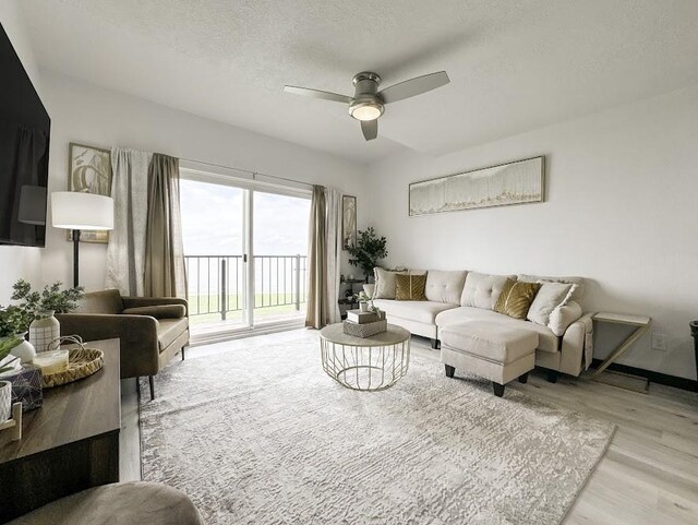 living room featuring a textured ceiling, light hardwood / wood-style floors, and ceiling fan