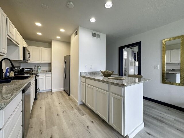 kitchen featuring sink, stainless steel appliances, white cabinetry, and light stone counters