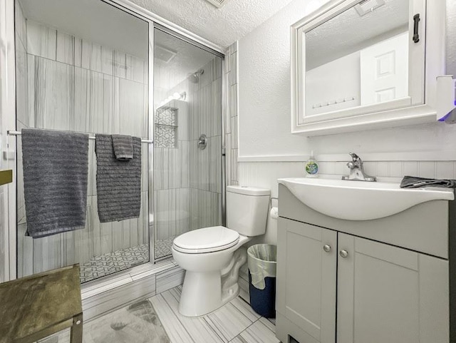 bathroom with vanity, a shower with shower door, a textured ceiling, and toilet