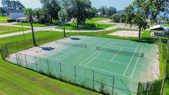 view of tennis court featuring a yard