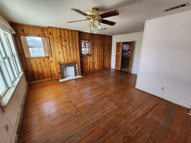 unfurnished living room featuring wooden walls, ceiling fan, and dark hardwood / wood-style flooring