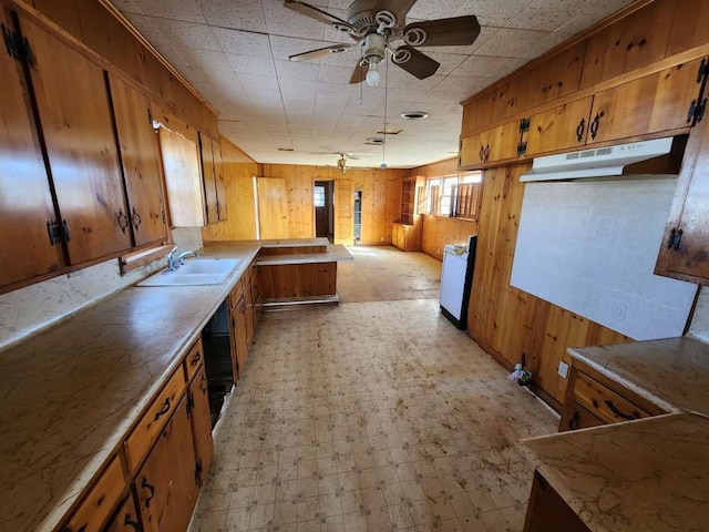 kitchen with wooden walls, sink, light tile flooring, and ceiling fan